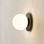 Round Glass Wall Sconce with Metal Backplate, close view at 45 degrees on a plaster wall