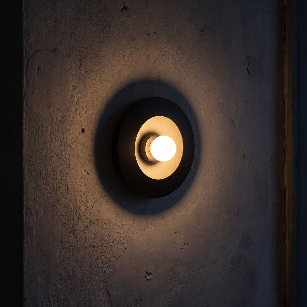 Round Iron Ring Wall Light with Magnetic Bulb glowing on a plaster wall at night