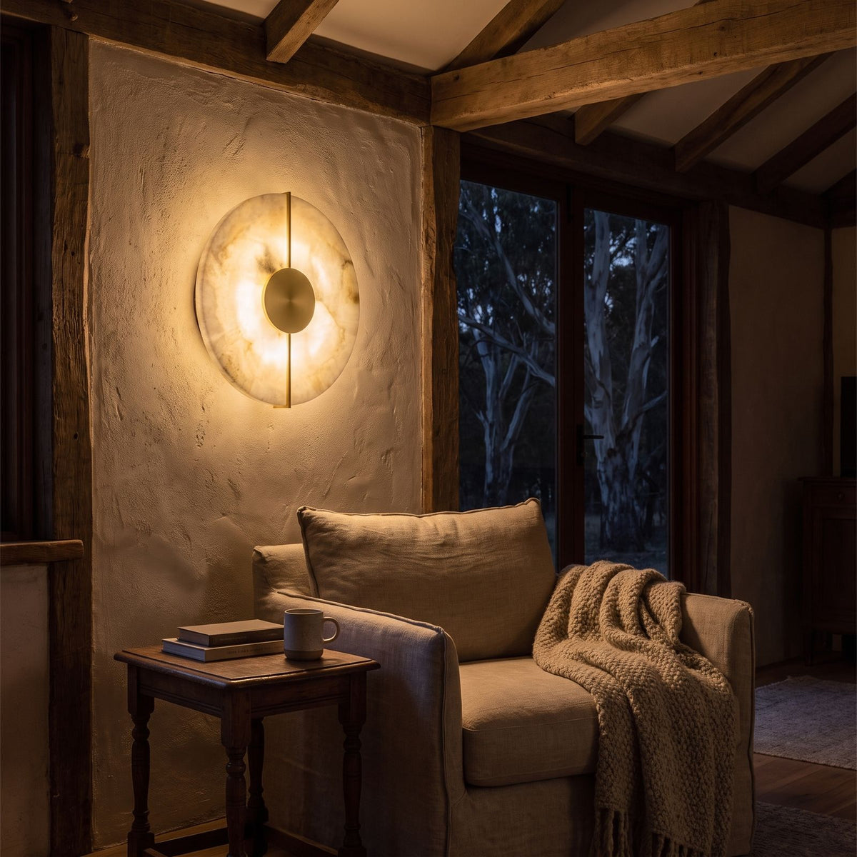Round Marble and Metal LED Wall Light beside an armchair at night