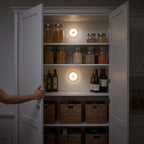 Two round motion sensor lights on the back wall of a kitchen pantry at night