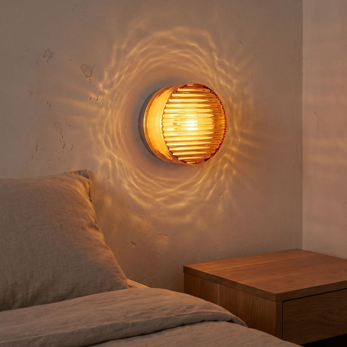 Round Ribbed Glass LED Wall Light beside a bed
