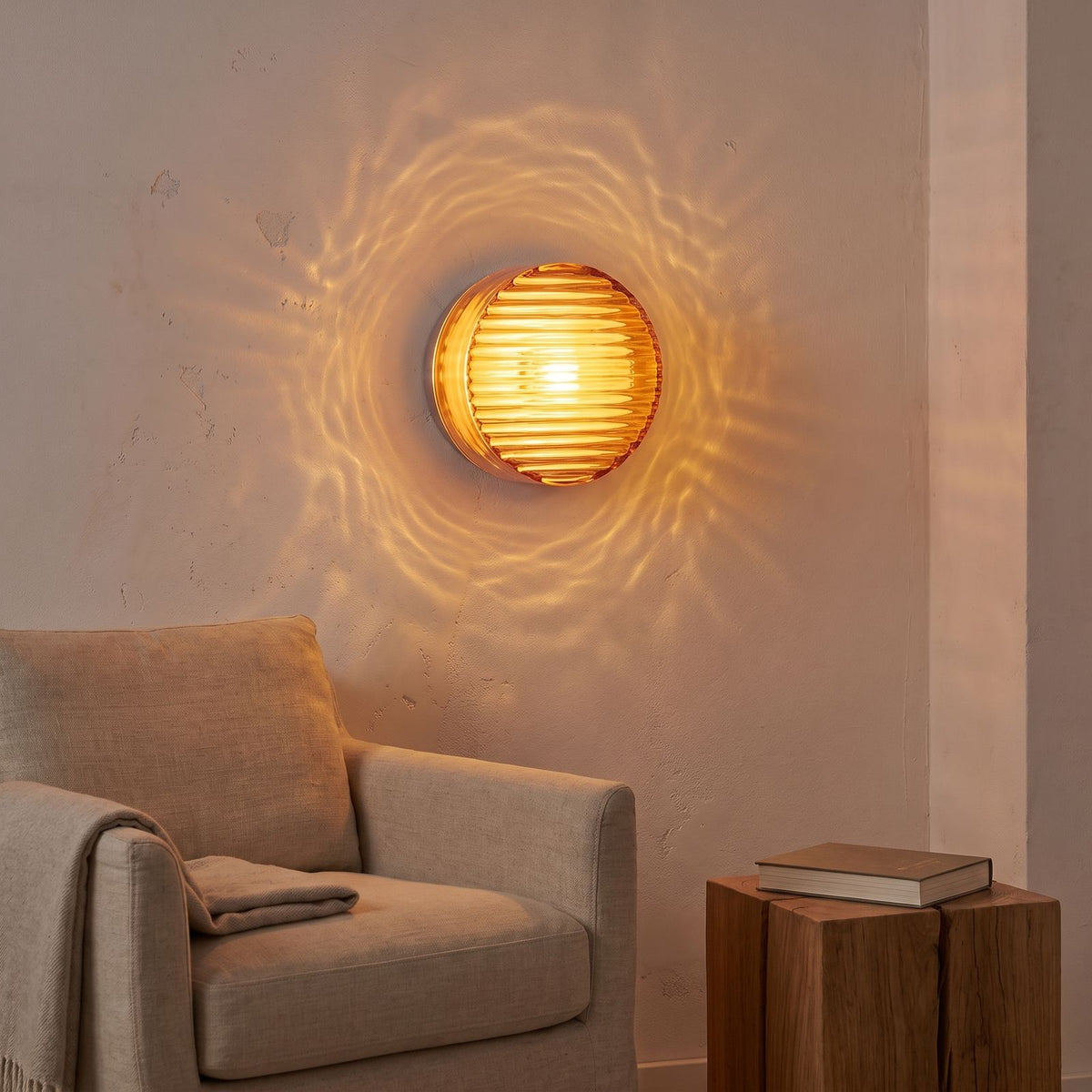 Round ribbed amber glass wall light above an armchair in a reading corner