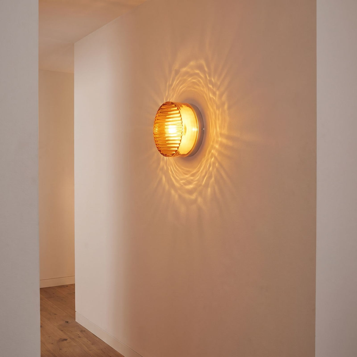 Round ribbed amber glass wall light on a hallway wall