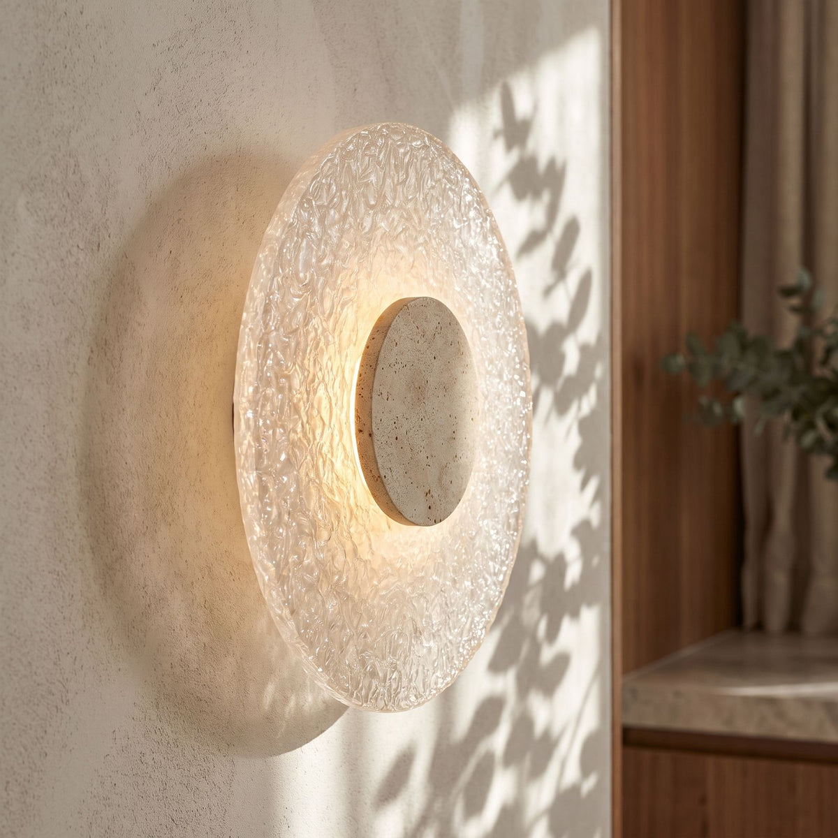 Round Travertine and Acrylic Wall Light on a plaster wall, angled close view