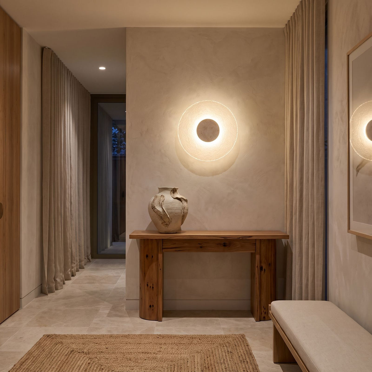 Round Travertine and Acrylic Wall Light above a timber console in an entry hallway