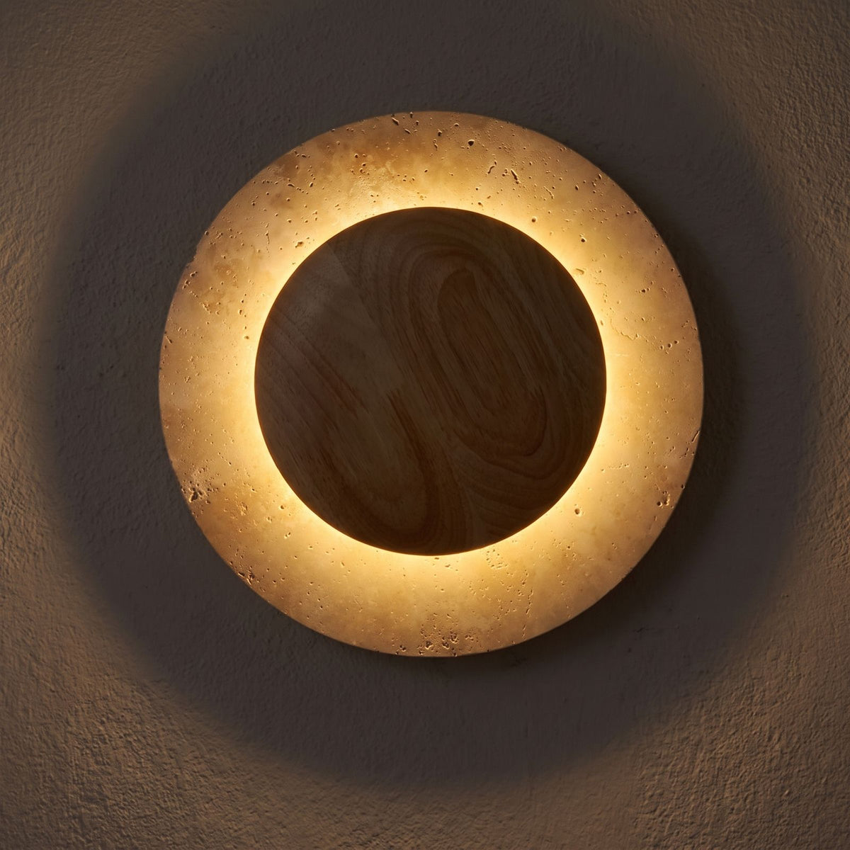 Round Travertine and Wood Shade LED Wall Light glowing on a plaster wall at night