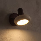 Round Travertine Swivel Bedside Wall Light glowing on a plaster wall at night