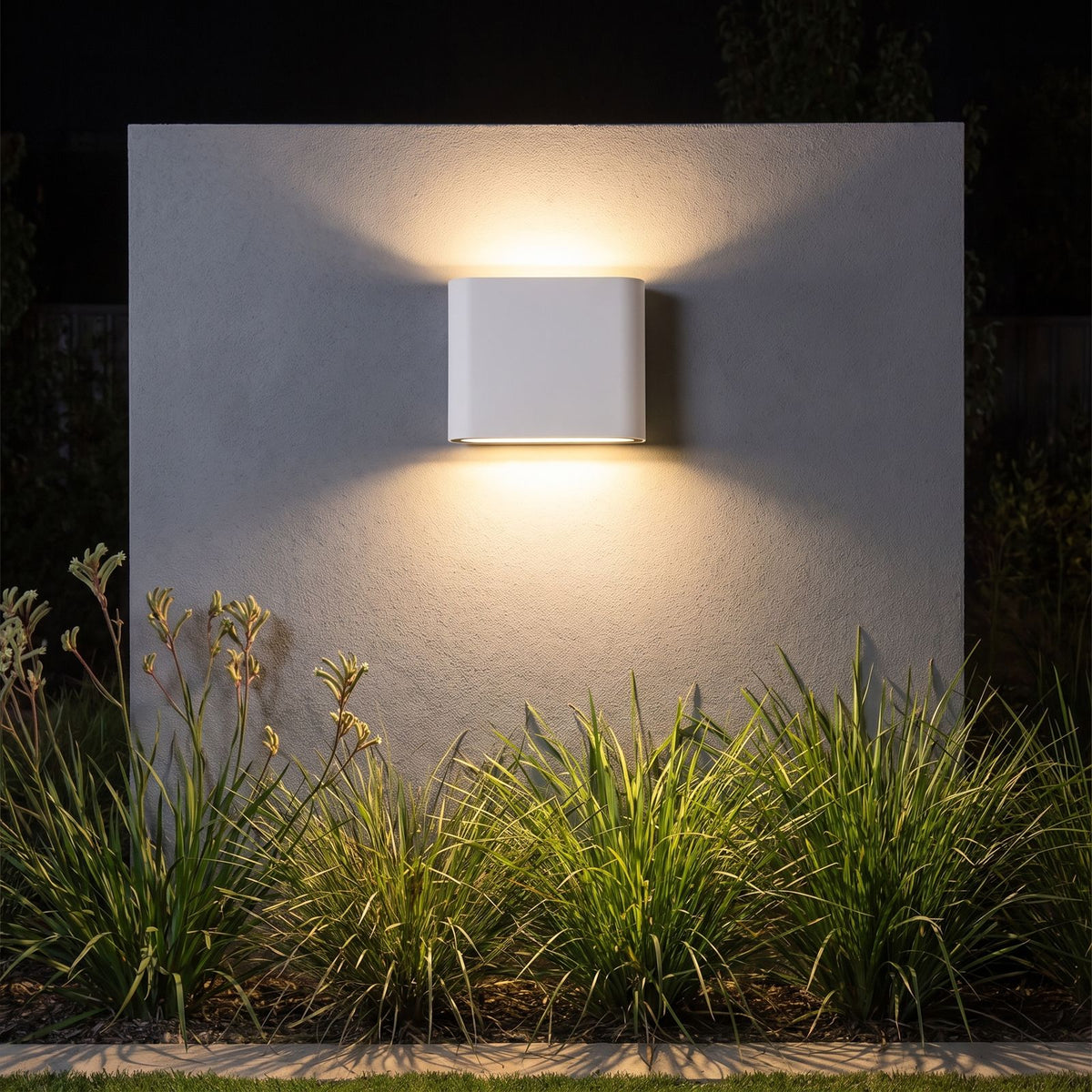 Rounded box up down outdoor wall light on a garden wall at night