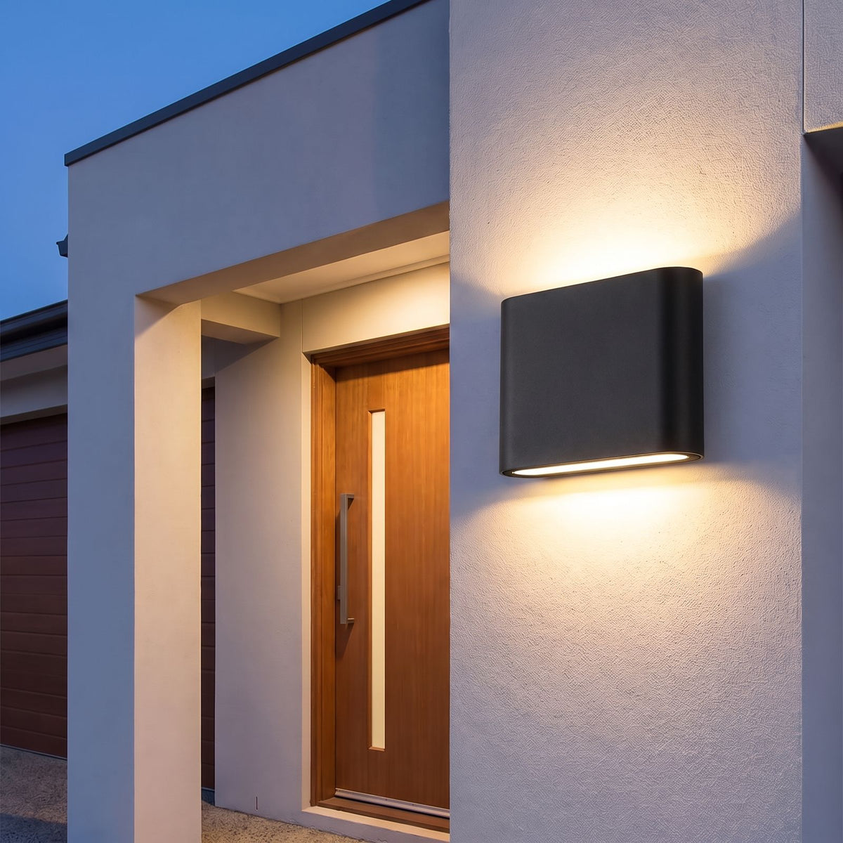 Rounded Box Aluminium Up Down Outdoor Wall Light in black beside a timber front door at dusk