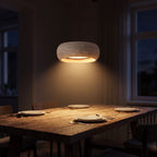 Rounded Travertine Puck LED Pendant Light above a dining table at night