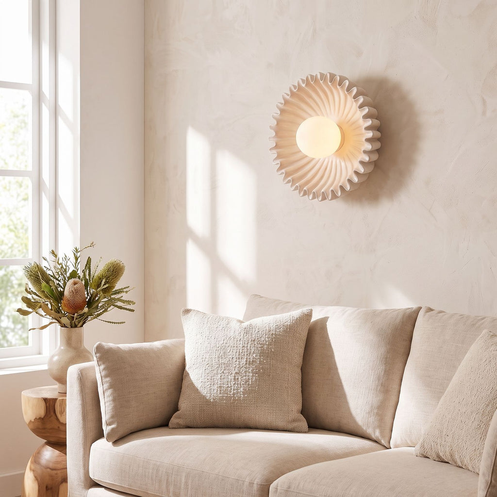 Ruffled ceramic flower wall light beside a living room sofa in daylight