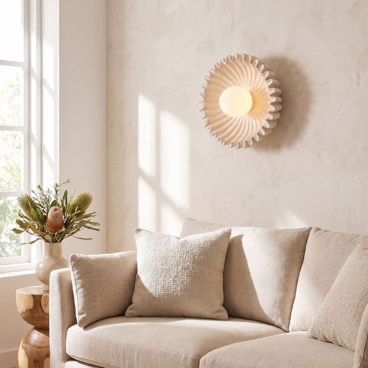 Ruffled ceramic flower wall light beside a living room sofa in daylight
