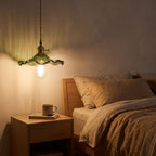 Ruffled fluted glass pendant light over a bedside table at night