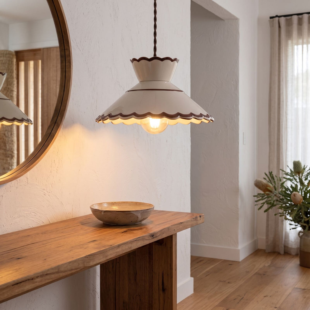 Scalloped cream ceramic pendant light above an entry hall console