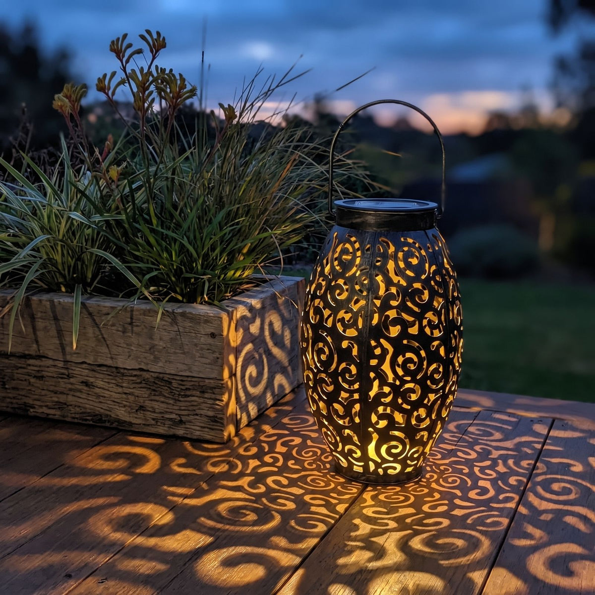 Scroll Pattern Metal Lantern Solar Garden Light on a timber deck at dusk
