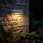 Semi Oval Stone Outdoor Wall Light glowing on a garden wall at night