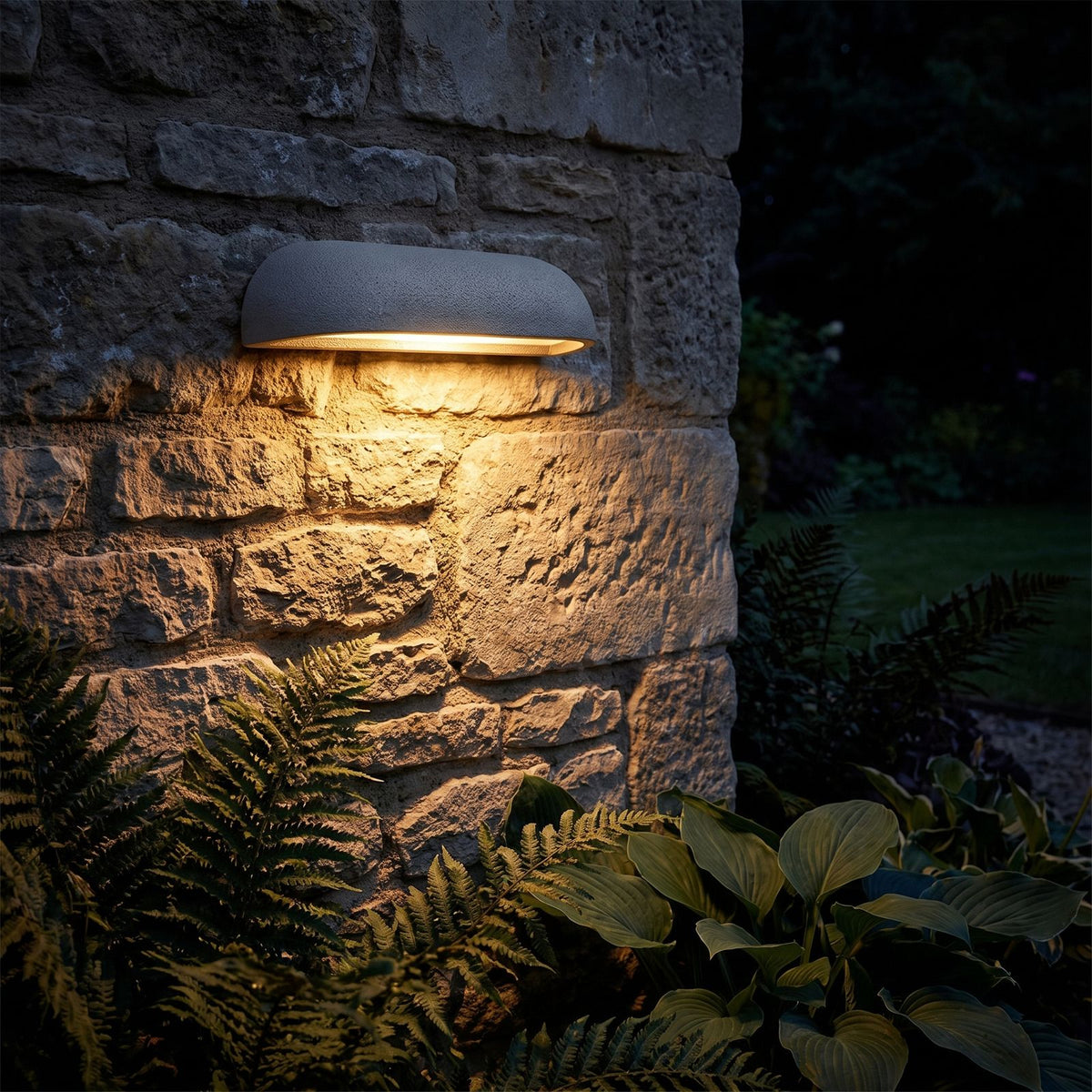 Semi Oval Stone Outdoor Wall Light glowing on a garden wall at night