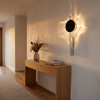Shadow Casting Aluminium and Glass Wall Light in a hallway above a timber console