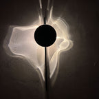 Shadow Casting Aluminium and Glass Wall Light glowing on a plaster wall at night