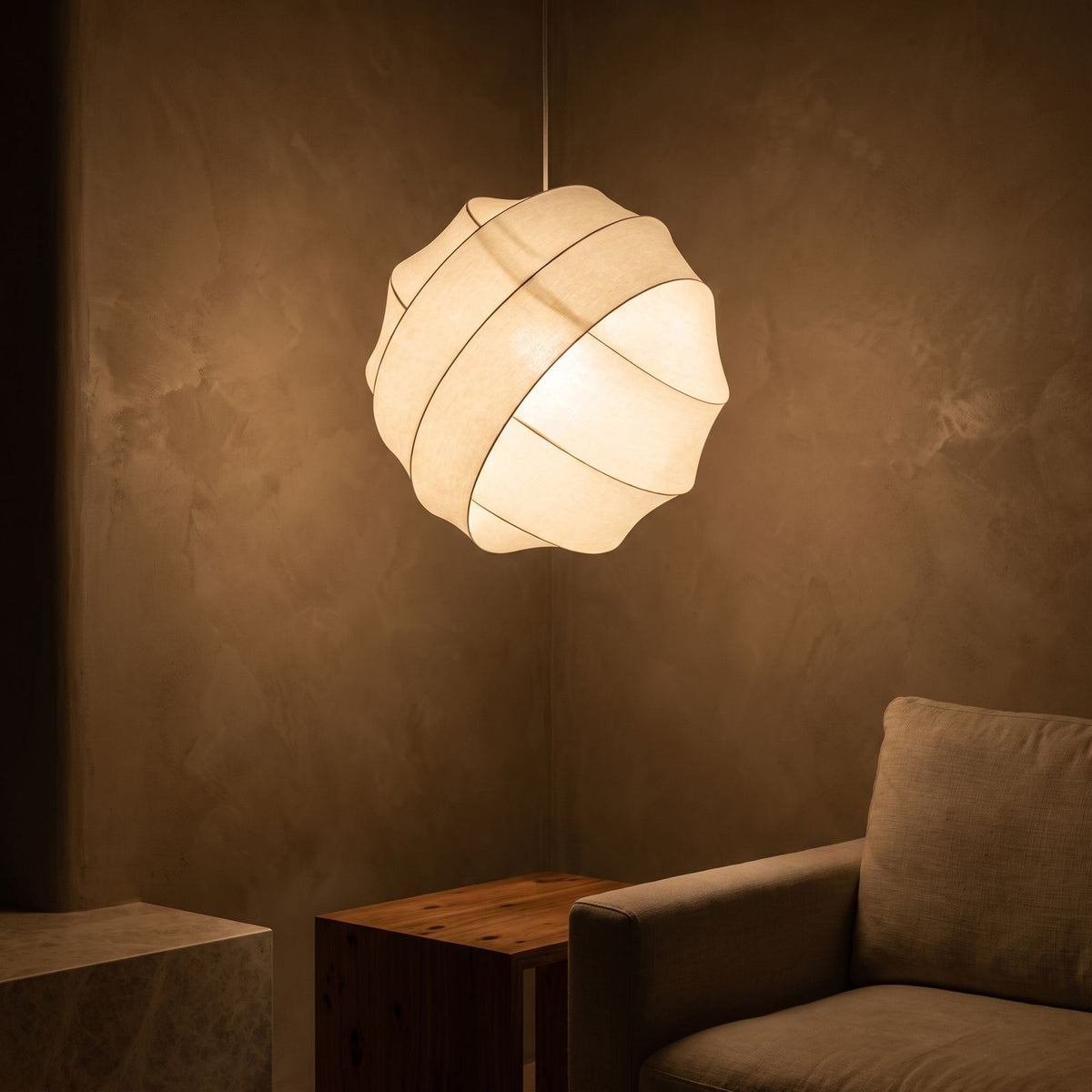 Silk Ball Japandi LED Pendant Light glowing against a plaster wall at night