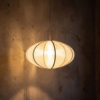Silk Pumpkin Lantern Japandi Pendant Light glowing against a plaster wall at night