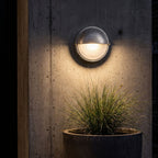 Silver Bulkhead Outdoor Wall Light lighting a concrete wall at night
