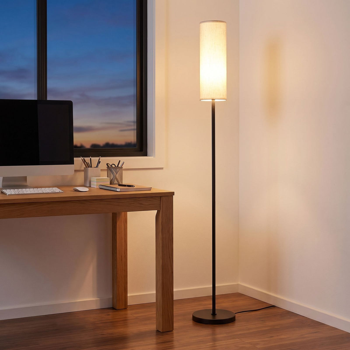 Fabric cylinder shade floor lamp in a home office corner beside a desk