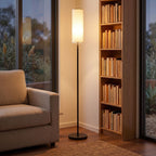 Fabric cylinder shade floor lamp in a reading corner beside a bookshelf