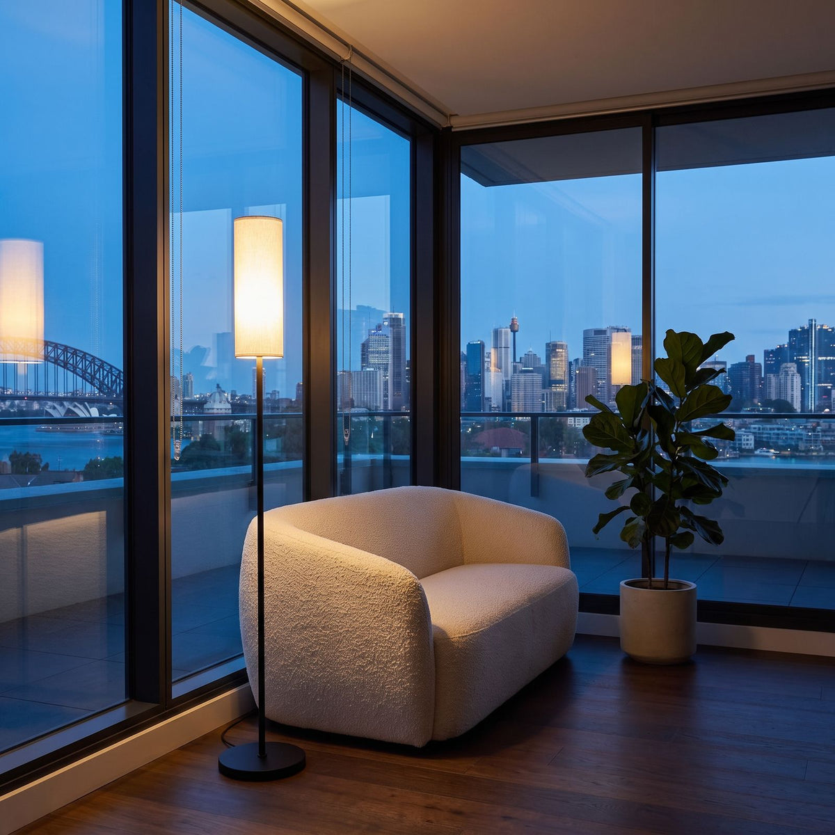 Slim black floor lamp lit beside the glass in a rooftop apartment lounge at dusk