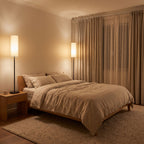 Slim black floor lamp used as a reading light beside a bed in a bedroom at night