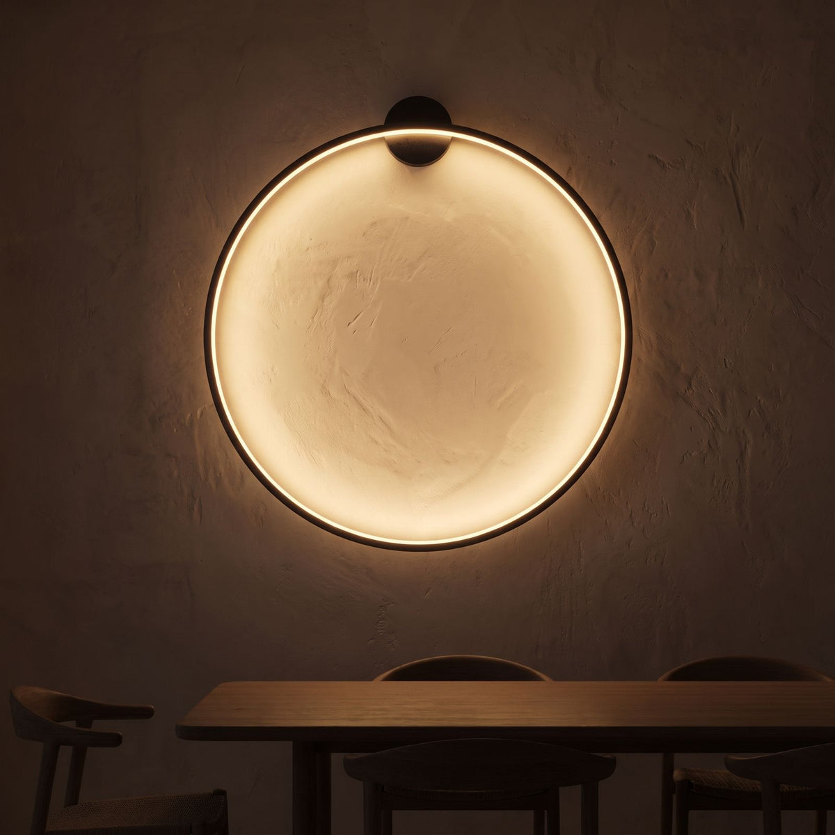 Slim black ring backlit LED wall light on a dining room wall at night
