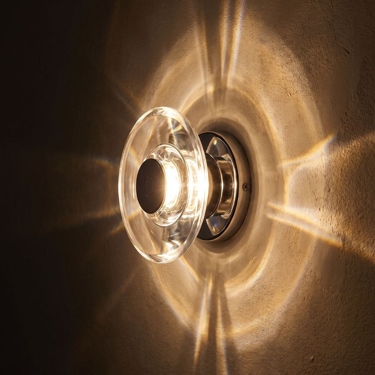 Slim Crystal Disc LED Wall Light glowing on a plaster wall at night