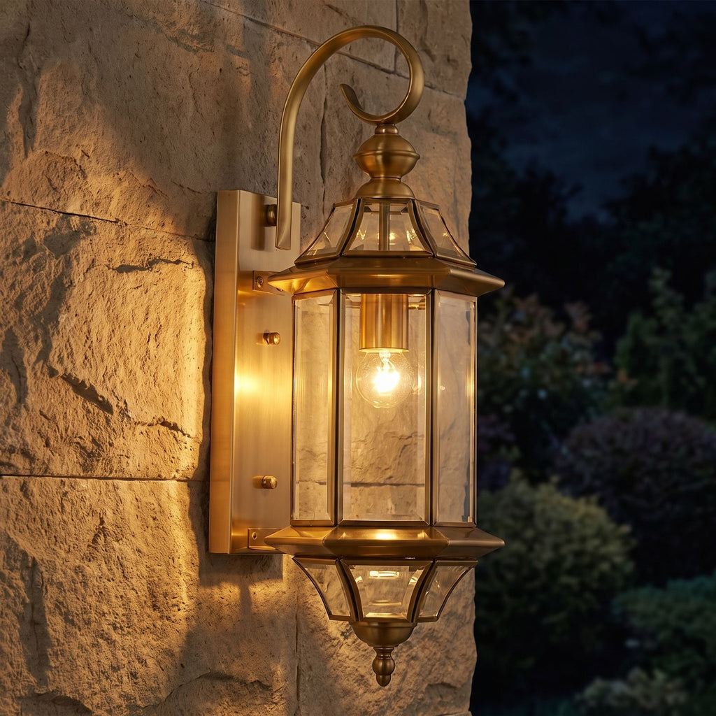 Slim Cylinder Brass Glass Outdoor Wall Light glowing on a garden wall at night