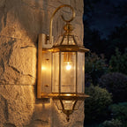 Slim Cylinder Brass Glass Outdoor Wall Light glowing on a garden wall at night