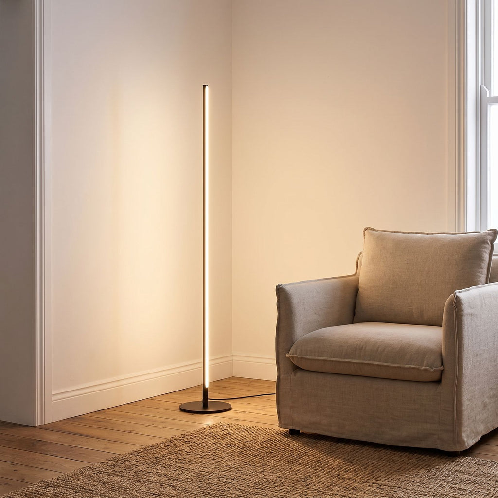 Slim Linear LED Aluminium Floor Lamp beside an armchair in a living room corner