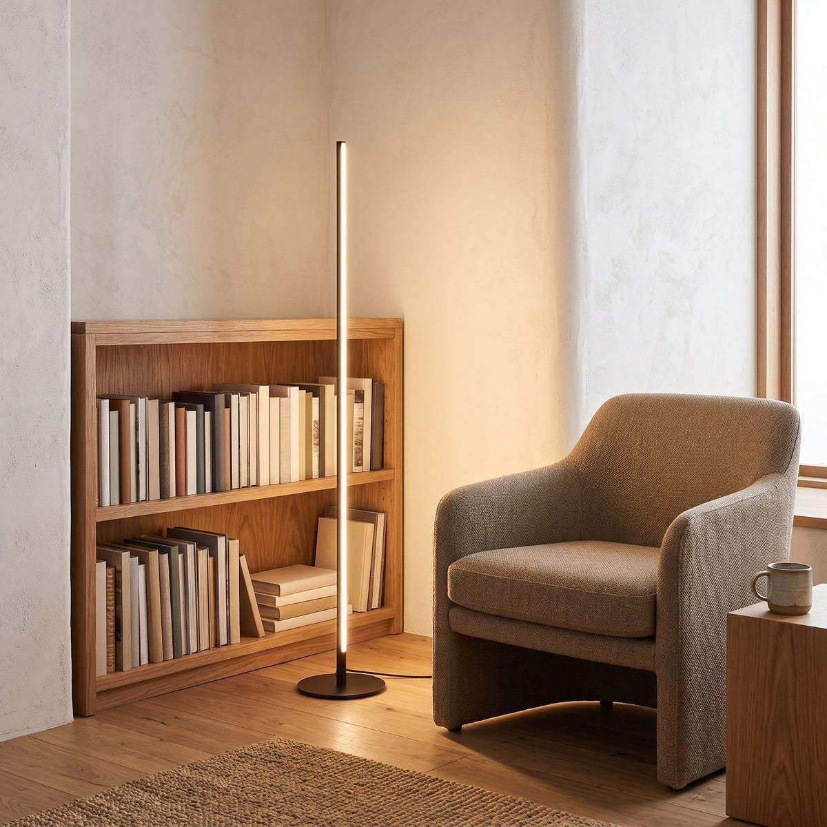 Slim linear LED floor lamp in a reading corner beside a bookshelf