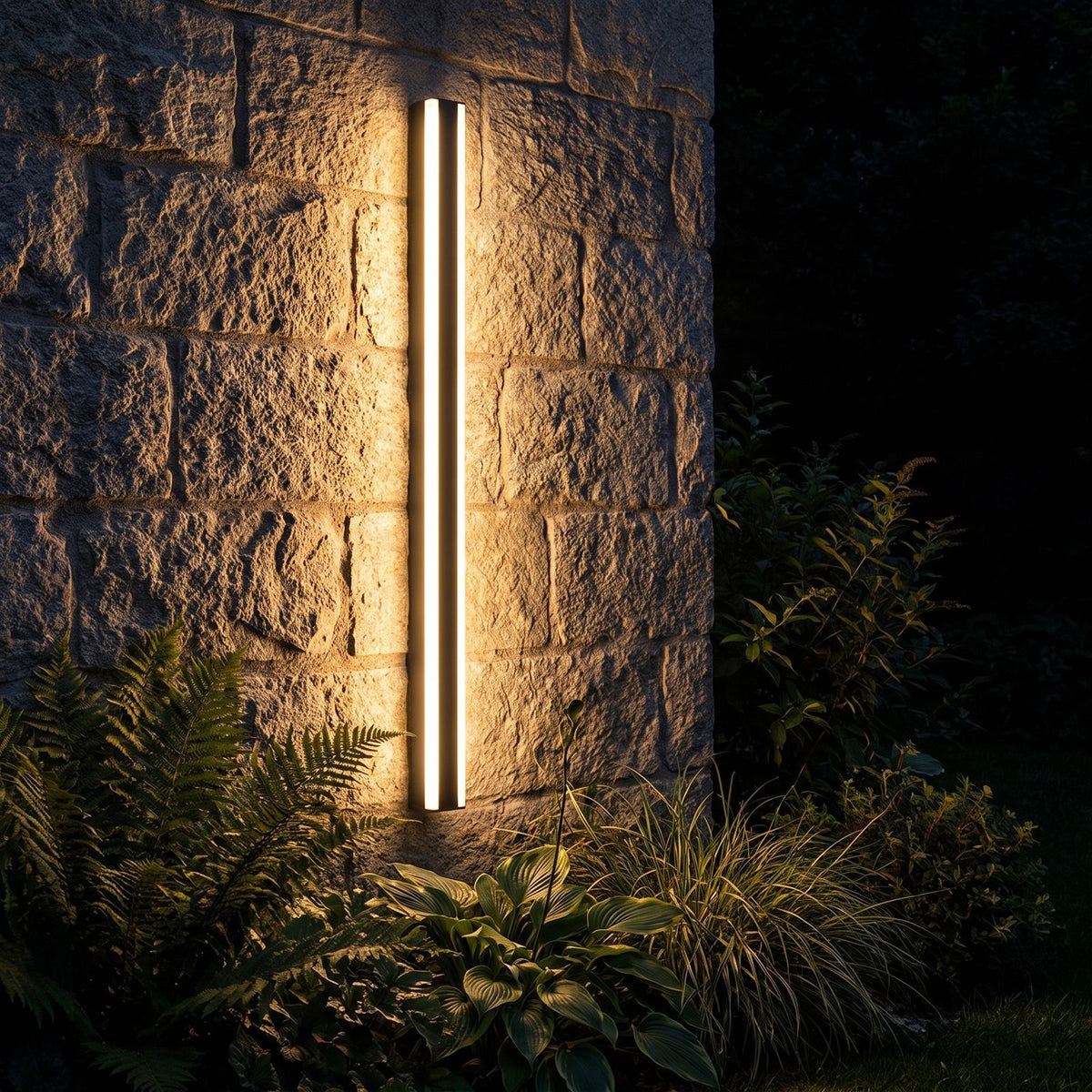 Slim Linear Metal Outdoor Wall Light glowing on a garden wall at night