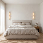 A pair of the marble tube wall lights either side of a bed in a bedroom, warm white light