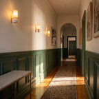 Three marble tube wall lights spaced along a hallway wall with green panelling