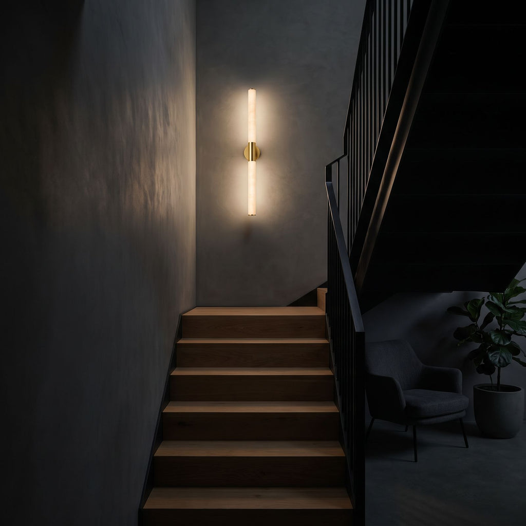 The marble tube wall light lit at night on a staircase wall, the only light in the stairwell