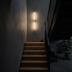 The marble tube wall light lit at night on a staircase wall, the only light in the stairwell