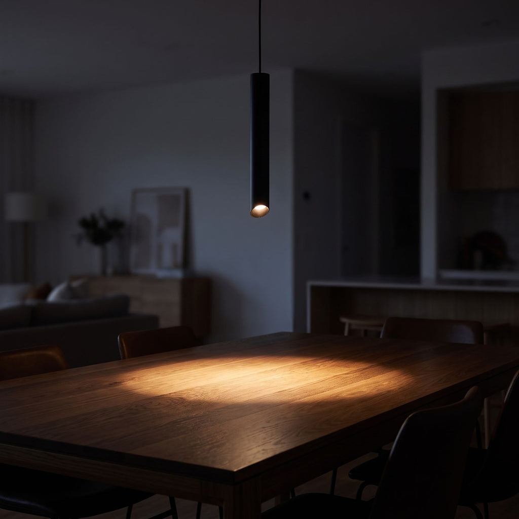 Slim metal cylinder pendant light over a dining table at night