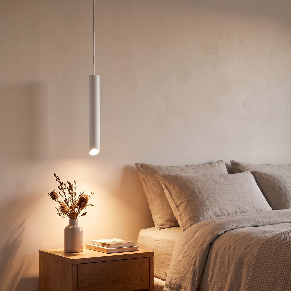 Slim Metal Cylinder Pendant Light in white beside a bed