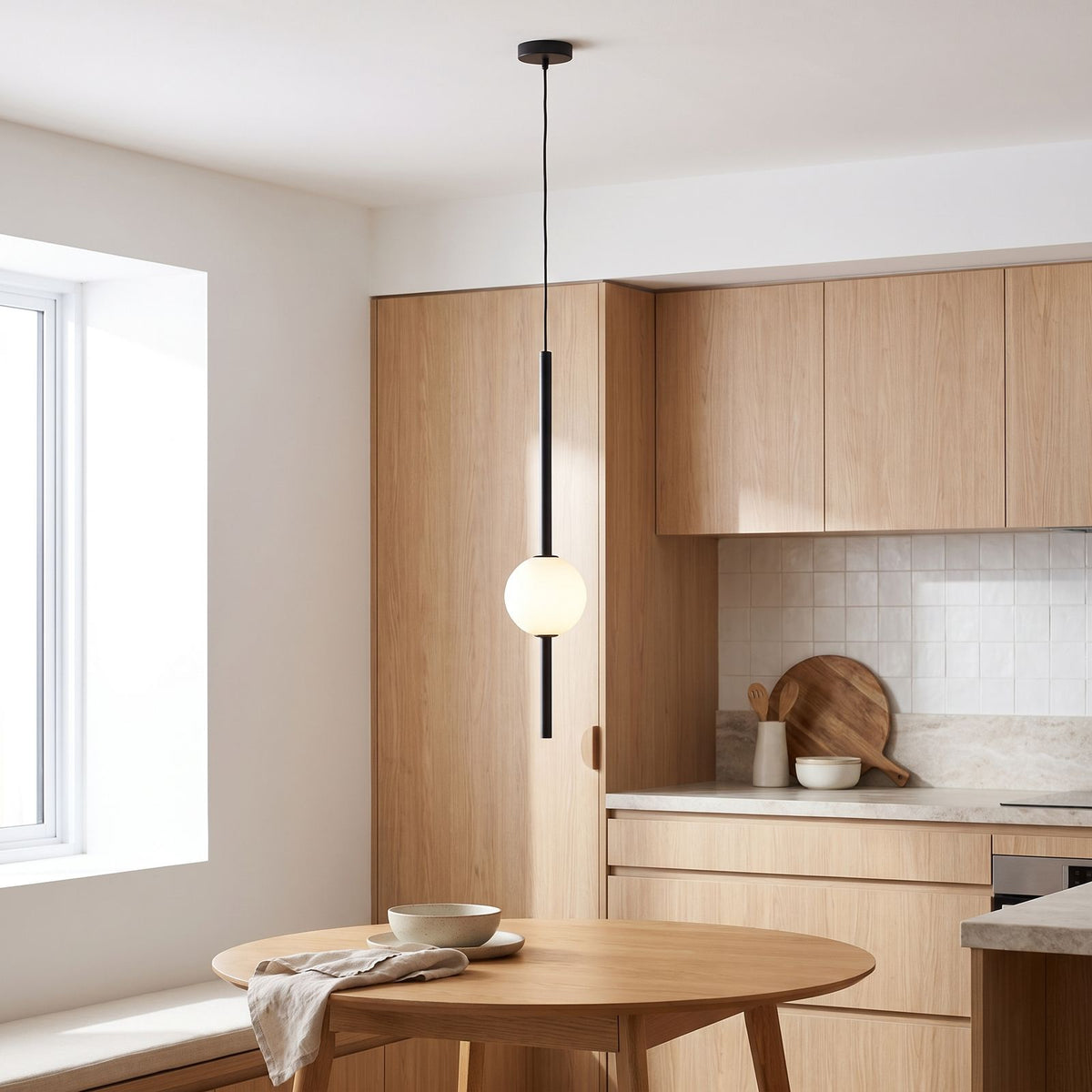 Slim rod frosted glass ball pendant light over a kitchen table in daylight