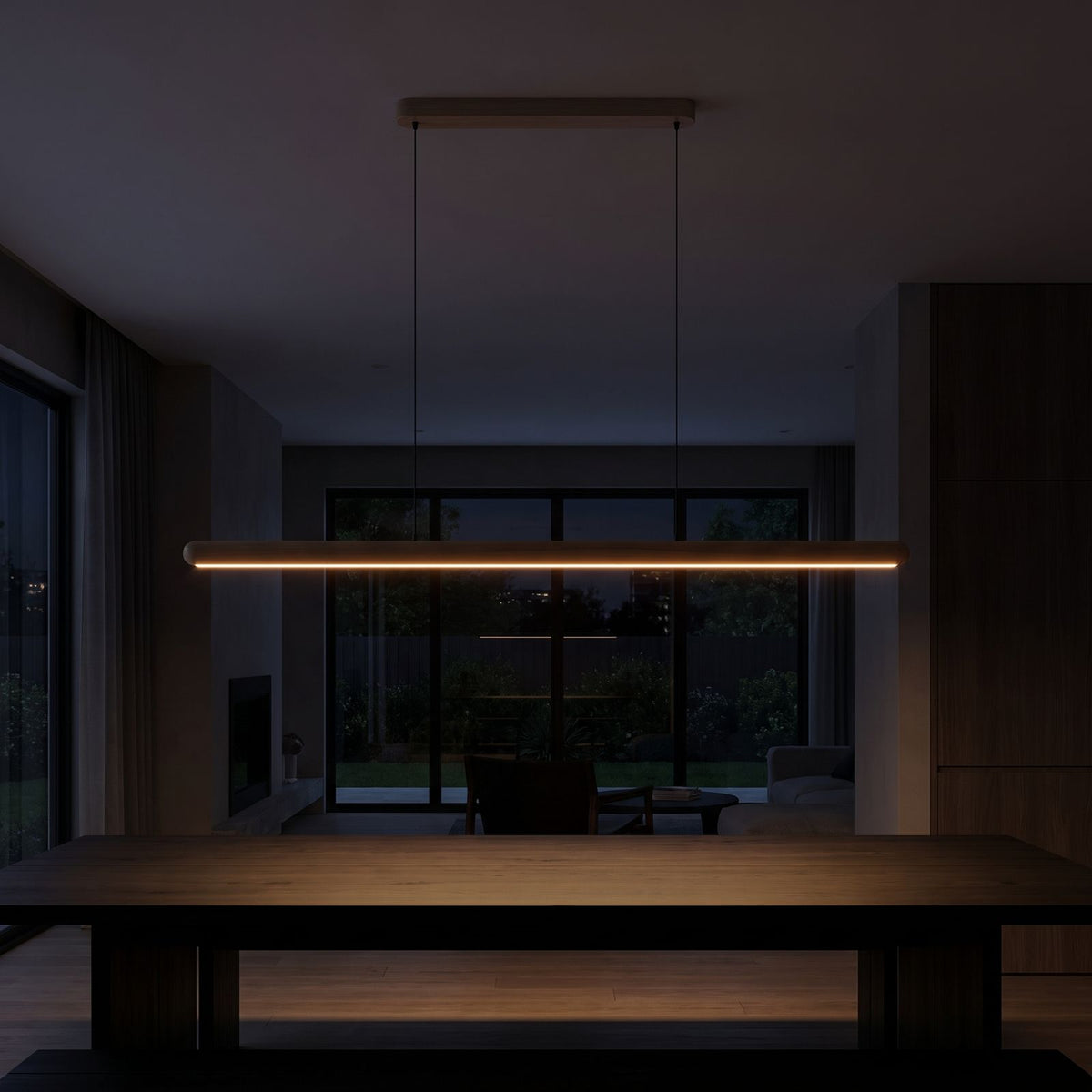 Slim wood bar linear LED pendant light over a dining table at night