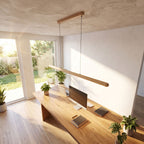 Slim wood bar linear LED pendant light above a home office desk in daylight