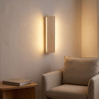 Slim wood plank wall sconce above an armchair in a reading corner