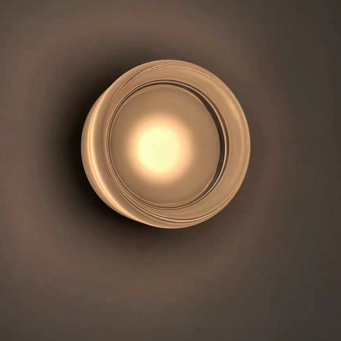 Smoked glass wall light glowing warm white on a dark wall