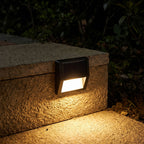 Solar LED Step and Deck Light glowing on a garden wall at night