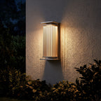 Solar Stainless Steel Box Outdoor Wall Light glowing on a garden wall at night